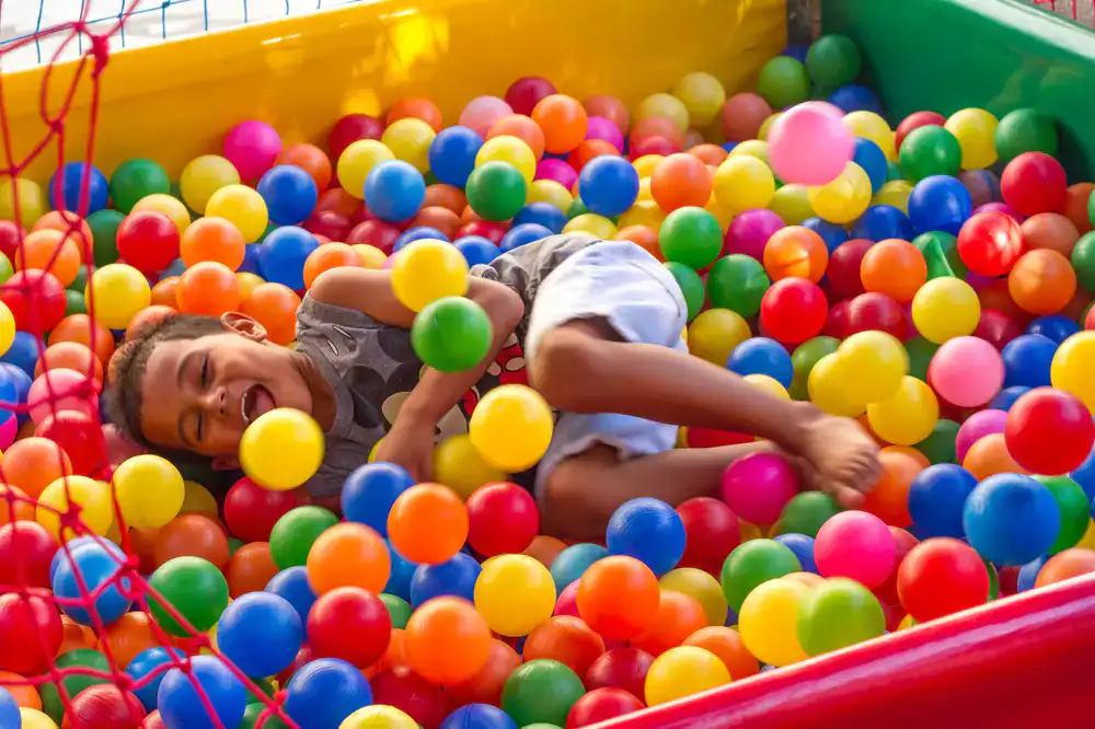 Children laughing and playing in a bright indoor soft play structure