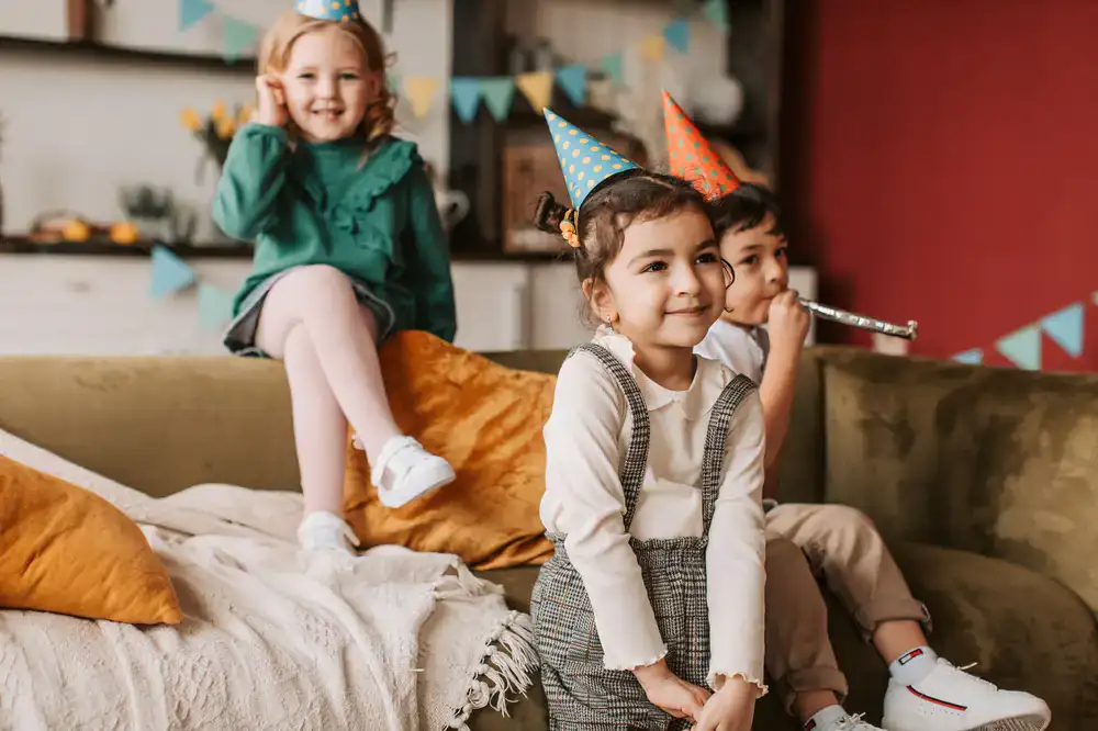 Children laughing and playing during a birthday celebration in a soft play area