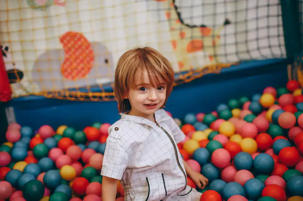 Child playing peacefully in a sensory-friendly soft play area with soft lighting